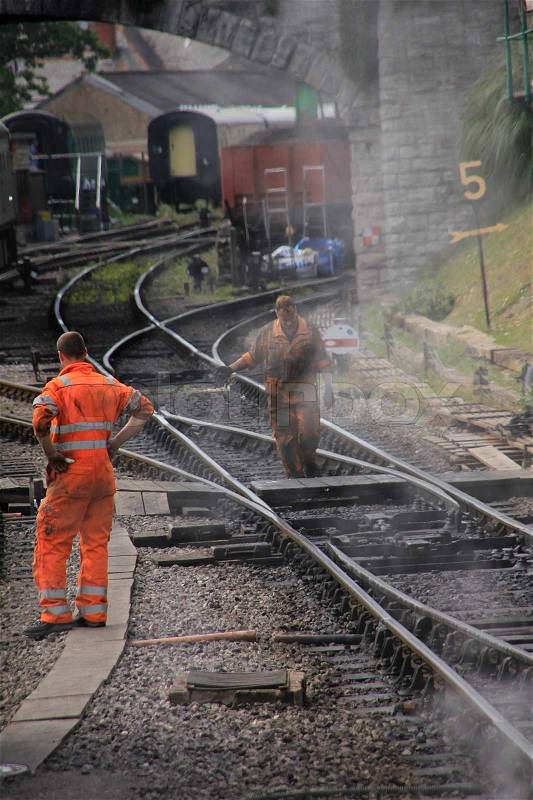 The men work on the rails in soiled fluorescent cloth on the station, stock photo