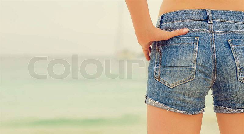 Woman in jeans near the sea. From the back, stock photo