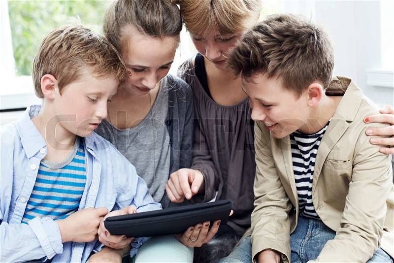 Siblings of mixed gender and age using a digital tablet, stock photo