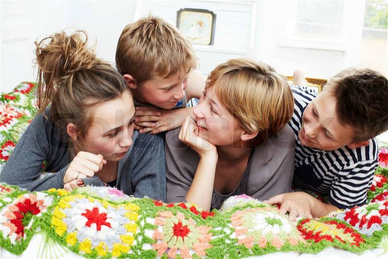 Four siblings lying on a bed, stock photo