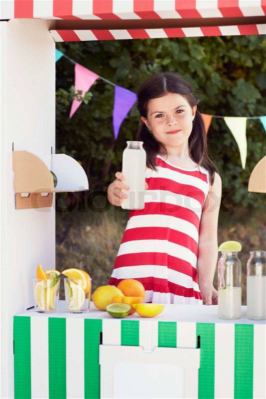 Young girl holding fruit juice bottle n fruit stall, stock photo