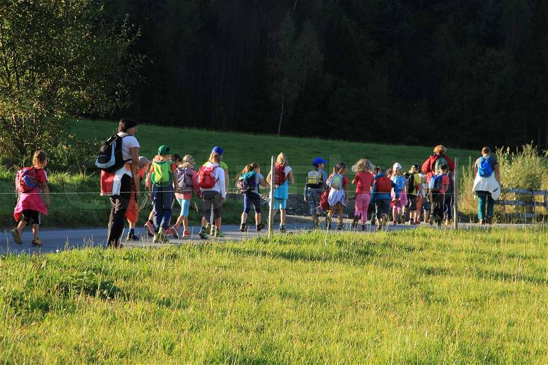 School class with teacher and volunteers walk to the mountains for a little walk in summertime, stock photo