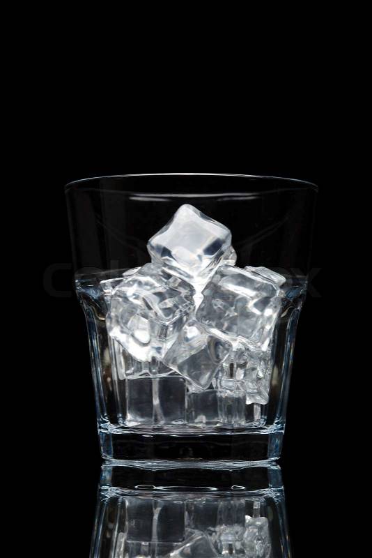 Glassful for whiskey with ice cubes isolated on black background, stock photo