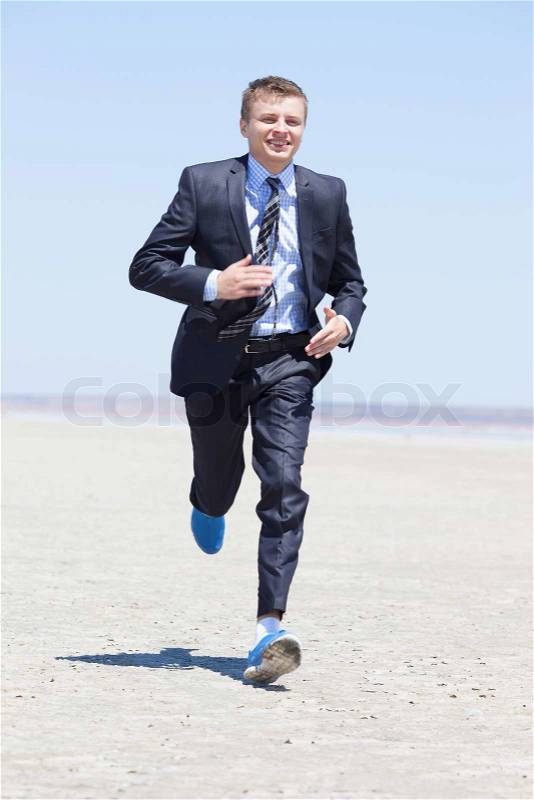 Businessman running in a desert, stock photo