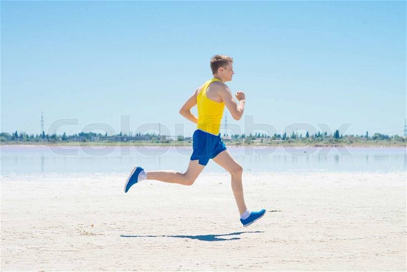 Young man jogging on the beach in summer, stock photo