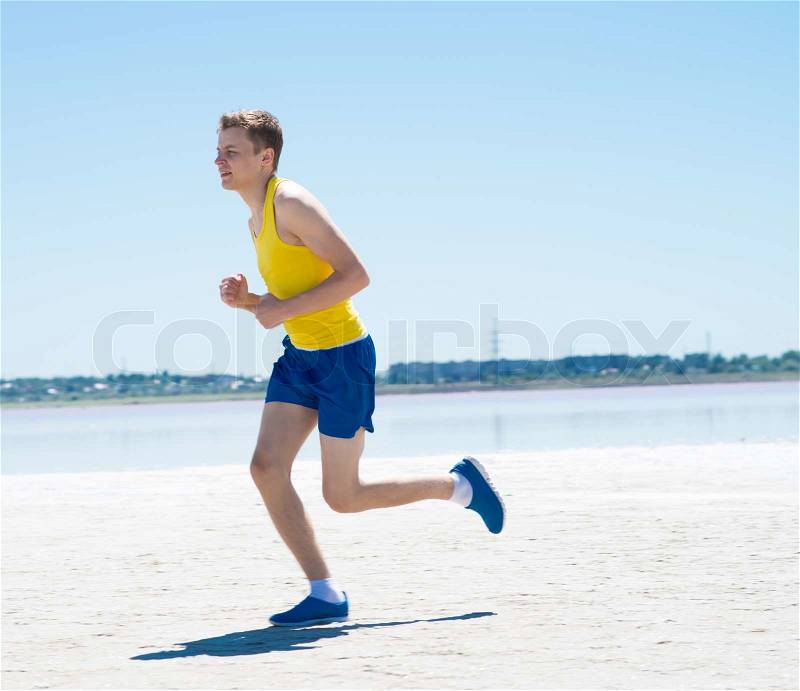 Young man jogging on the beach in summer, stock photo