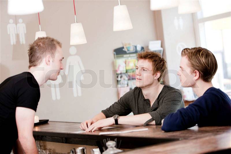 A bartender waiting for orders from two male customers, stock photo
