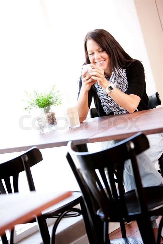 A lone caucasian woman in a restaurant with a smartphone and waiting for someone, stock photo
