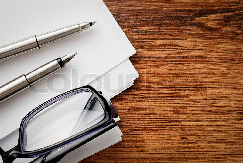 Close up Silver Pens, Blank Pages and Eyeglasses on Wooden Table with Text Area on the Right Side, stock photo