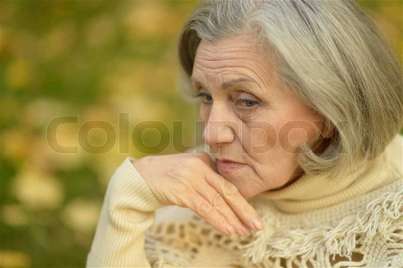 Nice sad old woman on the autumn background, stock photo