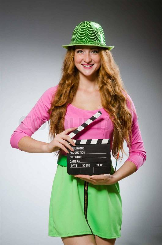 Woman in colourful dress holding movie board, stock photo