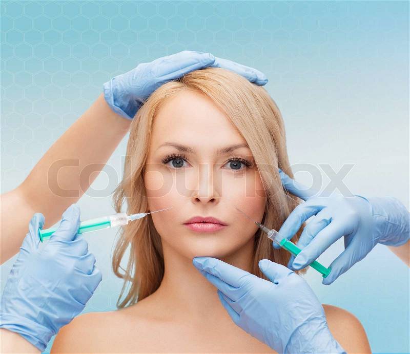 Beauty, people and plastic surgery concept - woman face and beautician hands with syringes, stock photo