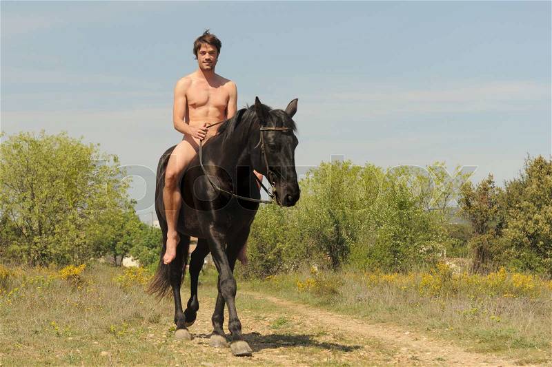 Naked young man and black stallion in the nature, stock photo