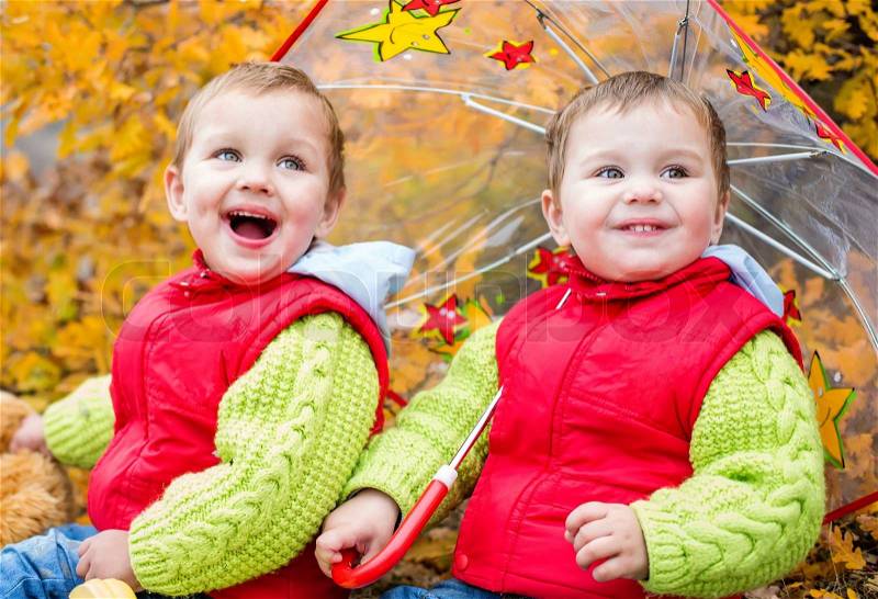 Happy toddler children under an umbrella in the autumn, stock photo