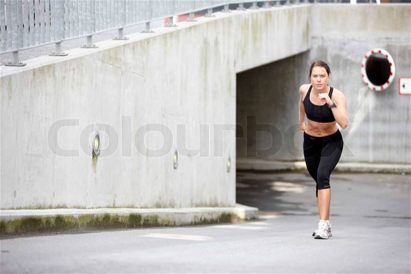 A young brunette caucasian woman in black sportswear ready to run, stock photo