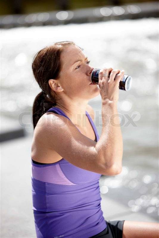 A young female brunette caucasian in sportswear drinking energy drink, stock photo