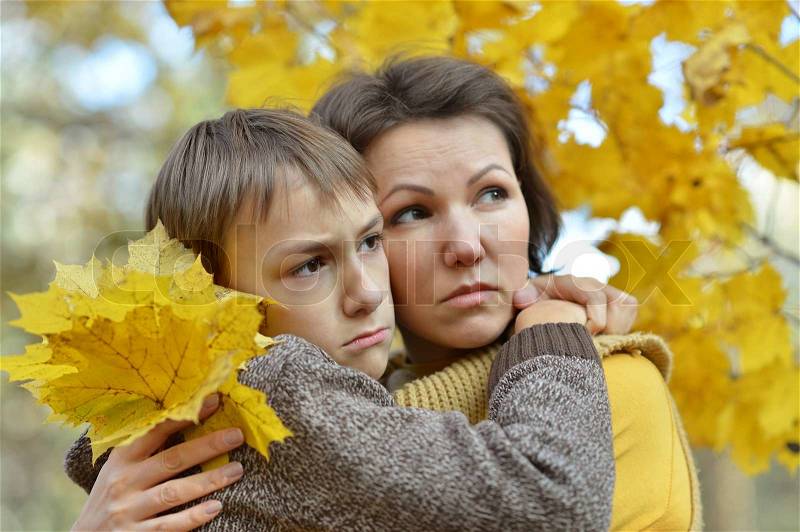 Sad mother with a son in the autumn park, stock photo