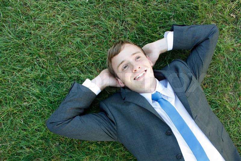 A business man lying on the grass, stock photo
