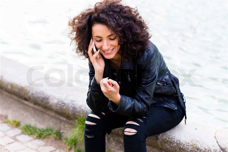 African woman telephoning with mobile phone at city fountain , stock photo