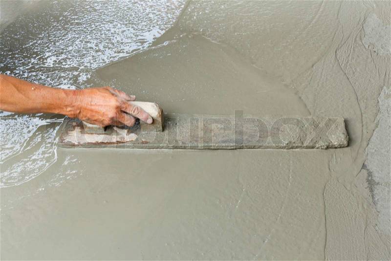 Close up worker hand using float to level surface of concrete, stock photo