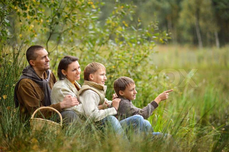 Family of four picking mushrooms in autumn forest,boy pointing on something, stock photo