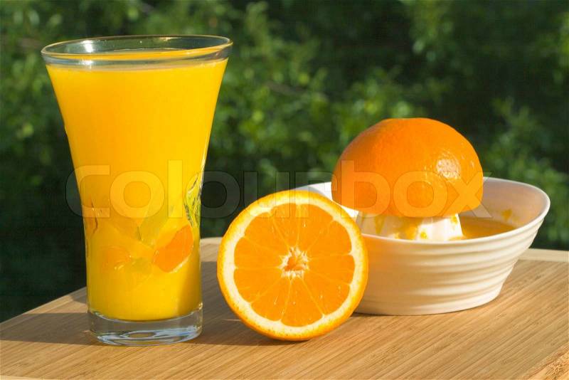 Glass Of Fresh Squeezed Organic Orange Juice - Juicer And Oranges With Natural Outdoor Background, stock photo
