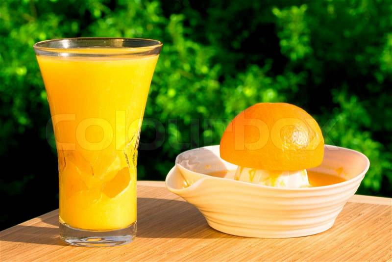 Glass Of Fresh Squeezed Organic Orange Juice - Juicer And Orange With Natural Outdoor Background, stock photo