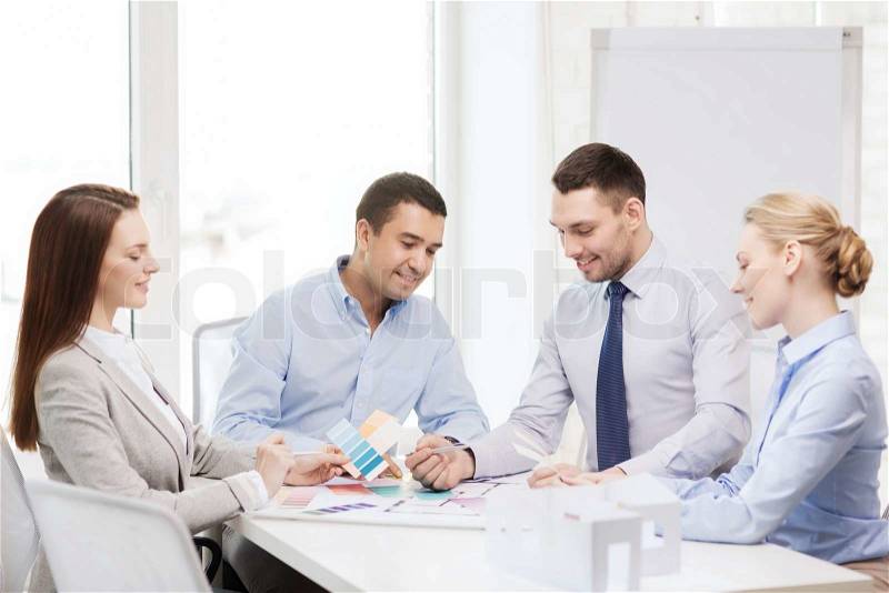 Business, architecture and office concept - happy team of architects and designers with color samples in office, stock photo