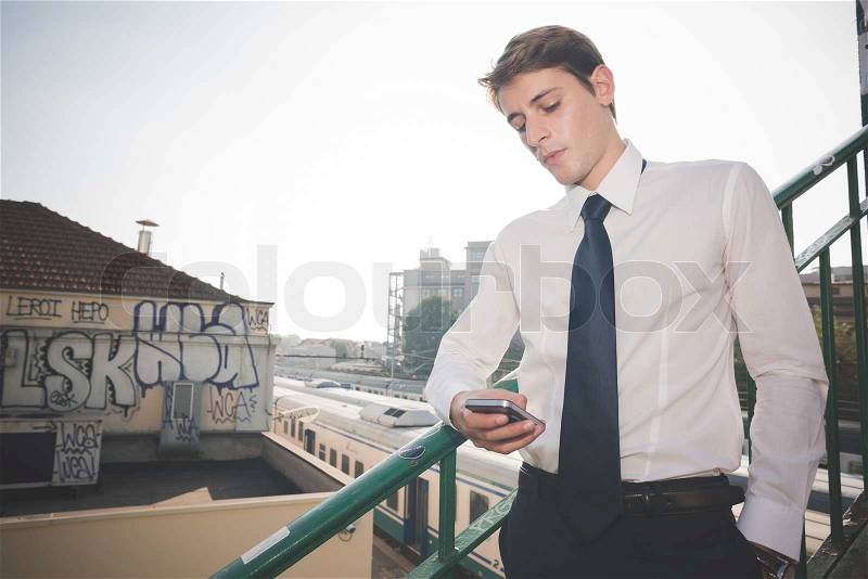Young handsome elegant blonde model man using smartphone in the city, stock photo
