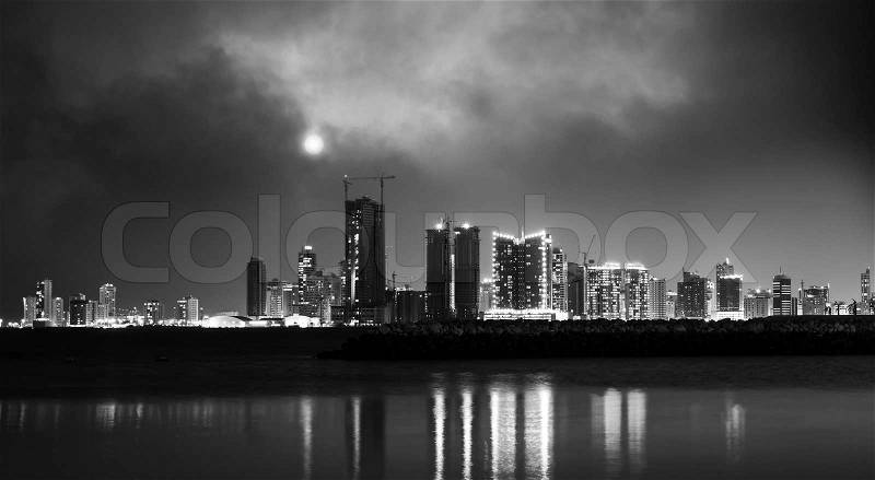 Black and white photo. Night modern city skyline with shining moon. Manama, the Capital of Bahrain, Middle East, stock photo