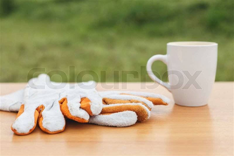 Close up coffee cup and safety glove on the table, stock photo