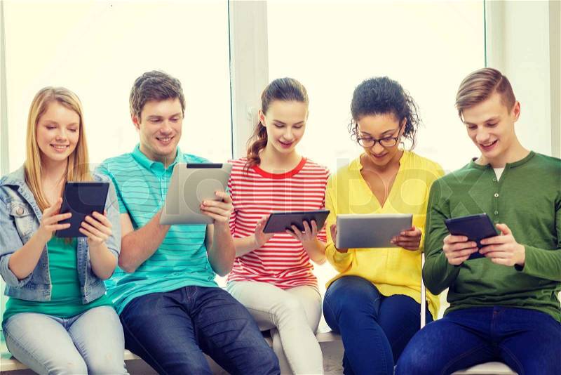 Education and technology concept - smiling students with tablet pc computer at school, stock photo