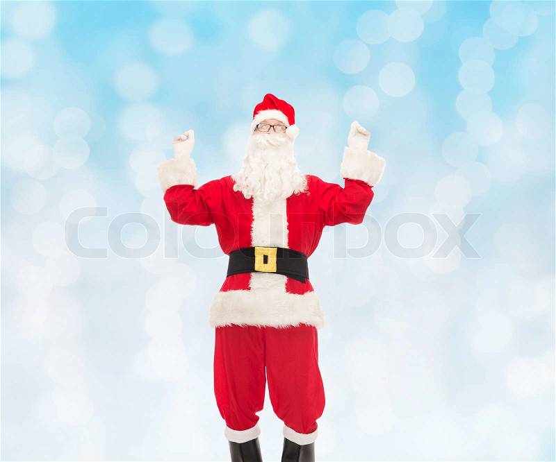 Christmas, holidays and people concept - man in costume of santa claus having fun over blue lights background, stock photo