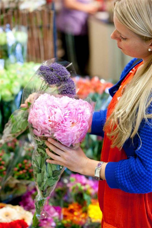 A young blond, caucasian woman in a supermarket buying flowers in a supermarket, stock photo