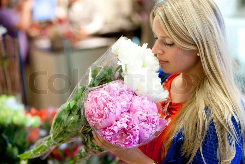 A young blond, caucasian woman in a supermarket buying flowers in a supermarket, stock photo