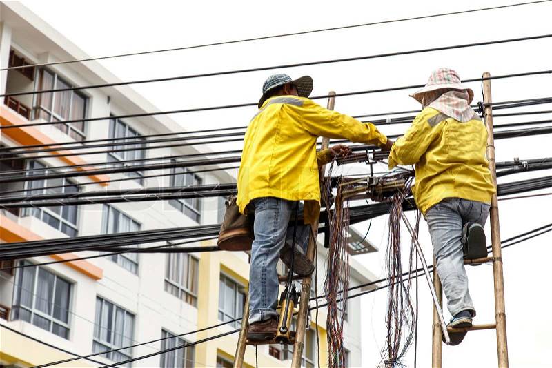 Worker on bamboo ladder is repairing telephone line, stock photo