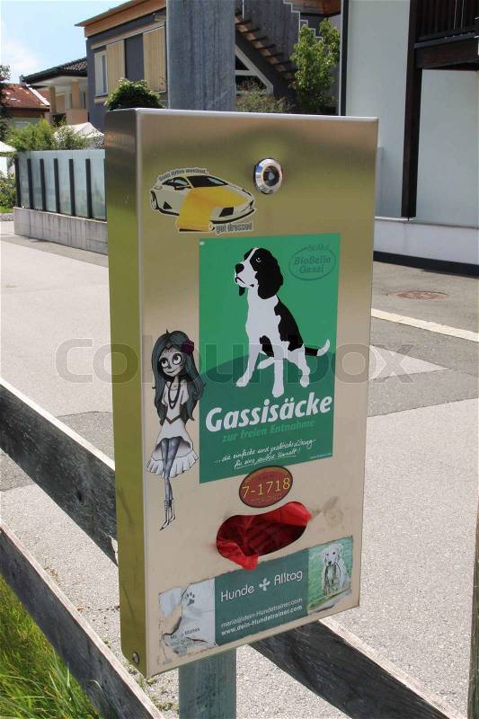 Take a free plastic red bag from the vending machine to clean up the droppings from the dogs in Austria, stock photo