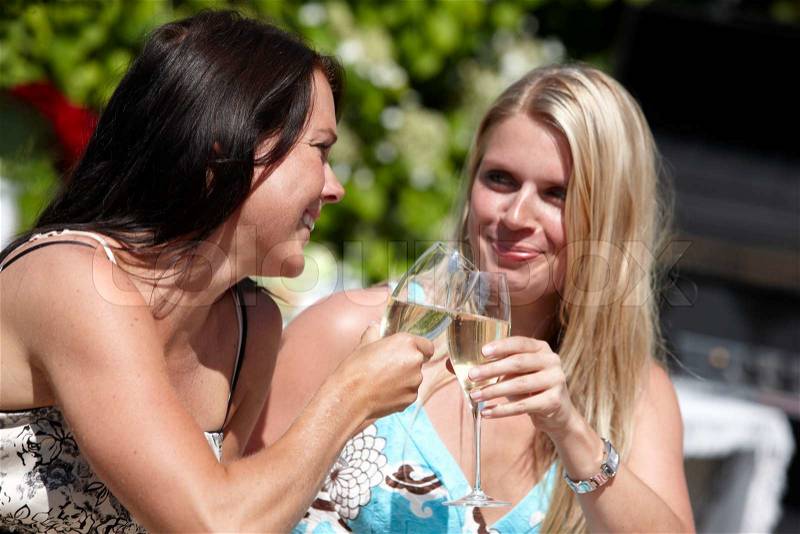 Two young caucasian women toasting on white wine during a summer lunch (stock photo), stock photo