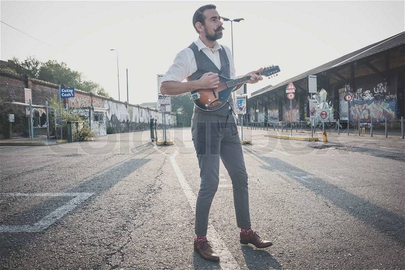 Handsome big moustache hipster man playing mandolin in the city, stock photo