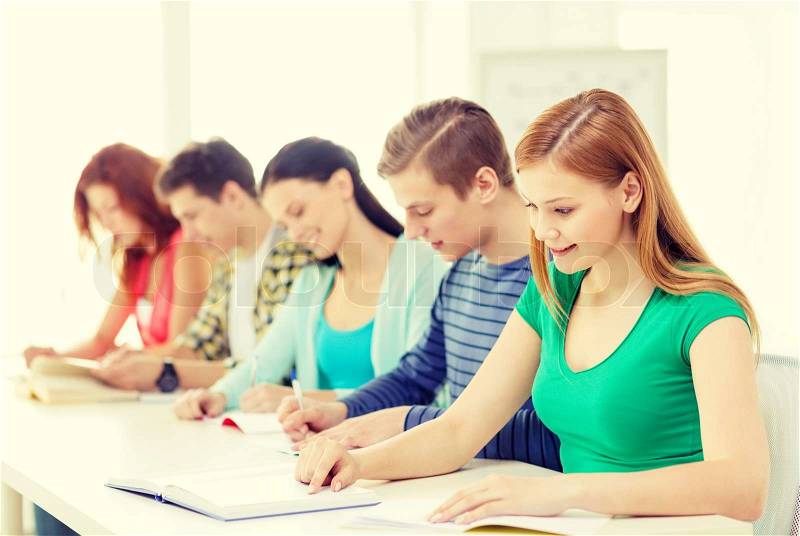 Education and school concept - five smiling students with textbooks and books at school, stock photo