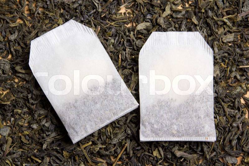 Two tea bags over dried tea leaves background, stock photo
