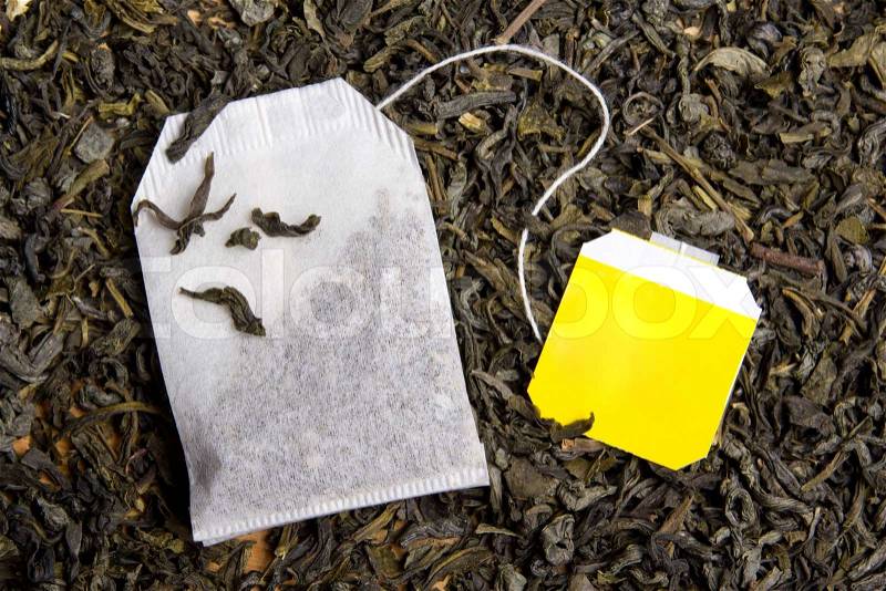 Background with dried black tea and paper tea bag, stock photo