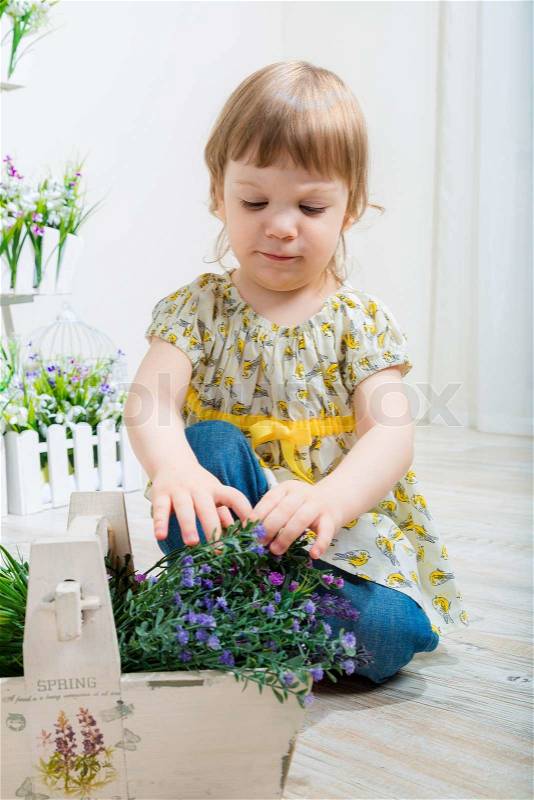 Cute little child girl with spring flowers, happy baby girl with basket of flowers, stock photo
