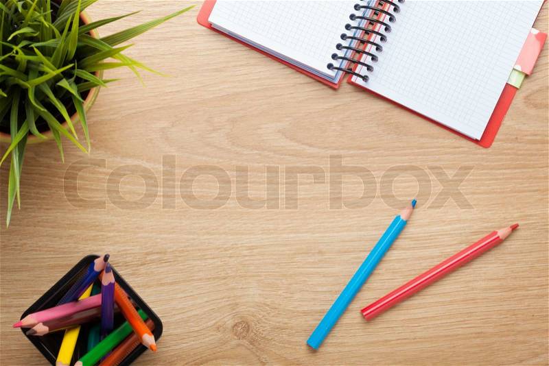 Office table with flower, blank notepad and colorful pencils. View from above with copy space, stock photo