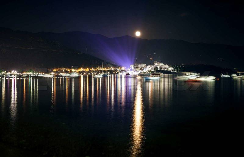 Beautiful landscape of moon shining over seaside city at dark night, stock photo