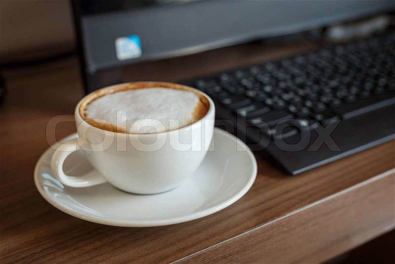 Coffee cup and computer on table, stock photo