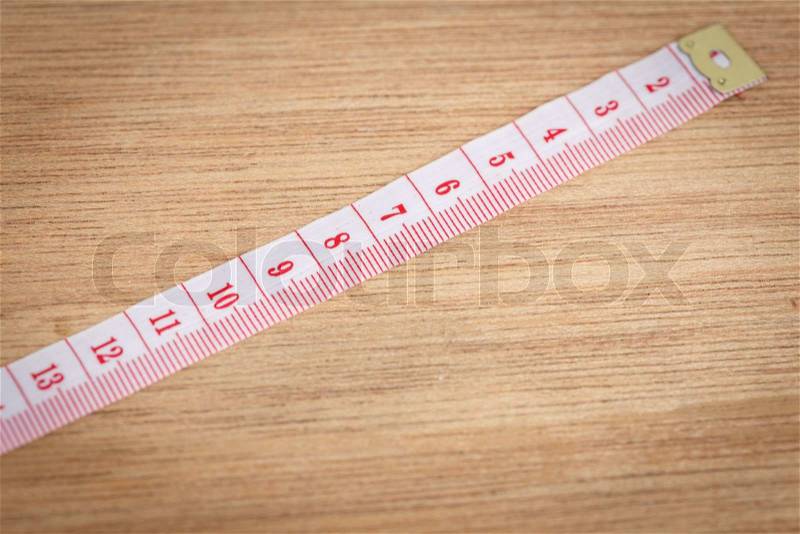White measure tape on wood texture, stock photo