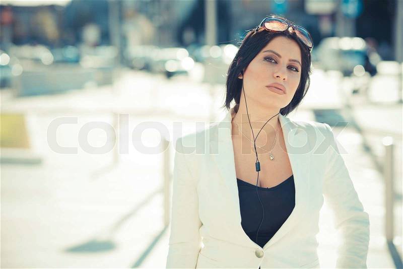 Beautiful long black hair elegant business woman with earphones in the city, stock photo