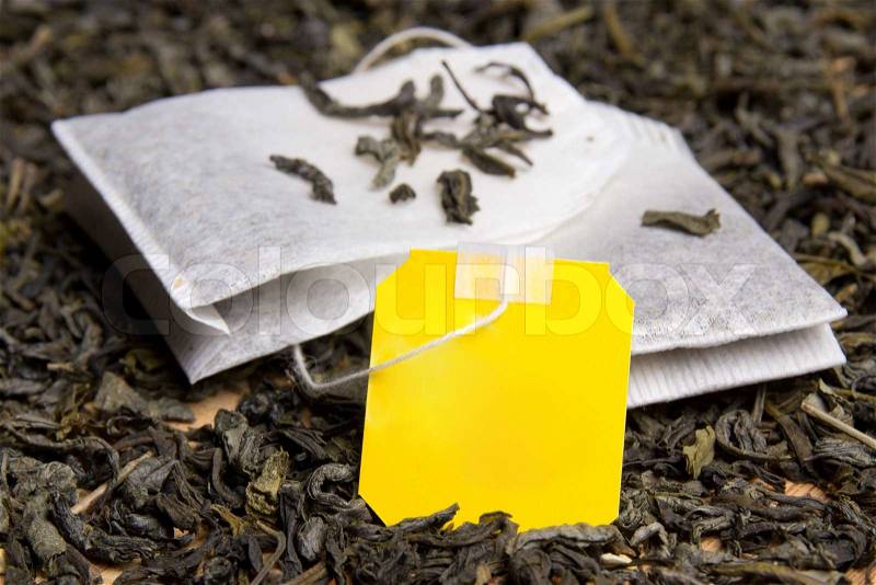 Close up picture of two tea bags and dried tea leaves with blank yellow paper, stock photo