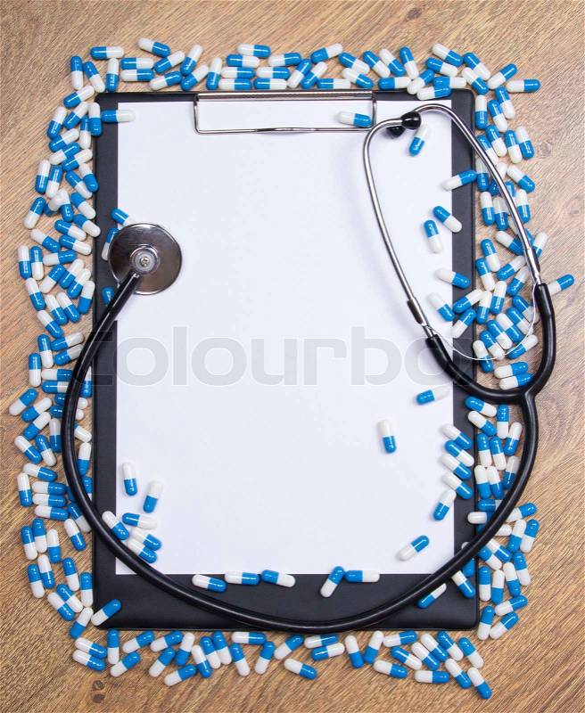 Pharmacy concept - heal of tablets, clipboard and stethoscope on wooden table, stock photo